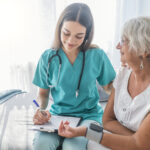 Nurse measuring blood pressure of senior woman at home. Smiling to each other. Young nurse measuring blood pressure of elderly woman at home. Doctor checking elderly woman's blood pressure