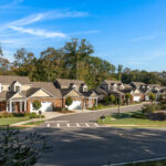 Row of suburban townhomes with attached garages under a clear blue sky.