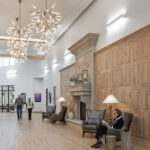 Interior showroom lobby with white walls, tall ceilings, and two large geometric chandeliers chandeliering the space.